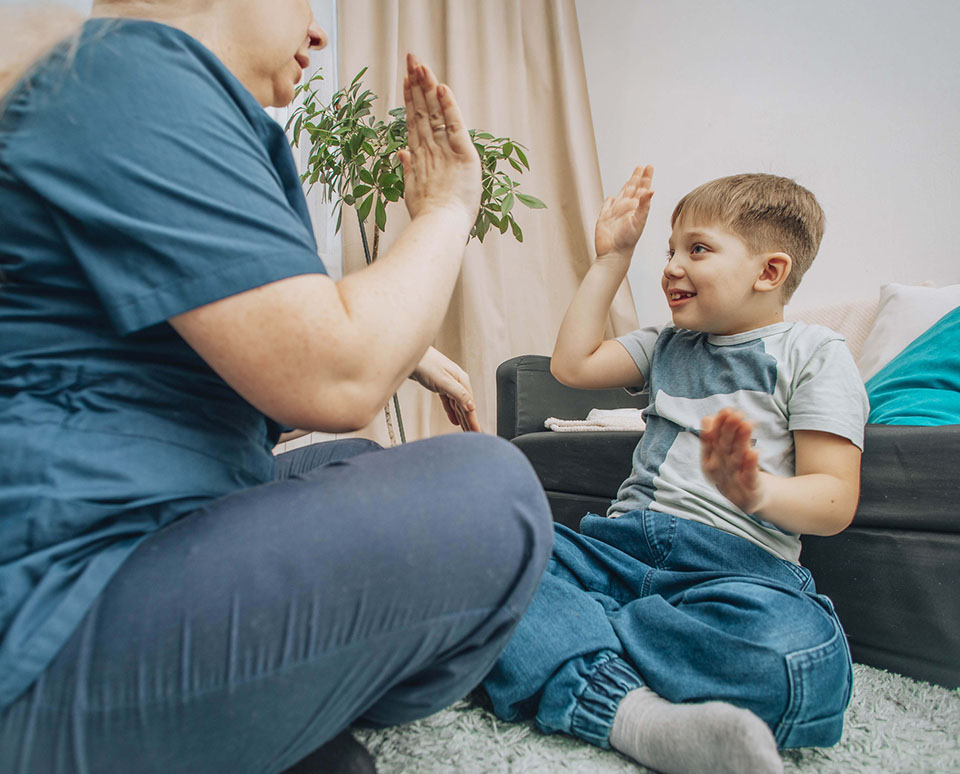 speech therapist engaging with young boy in nonverbal communication training, living room with warm decor, concept of education and cognitive skills development